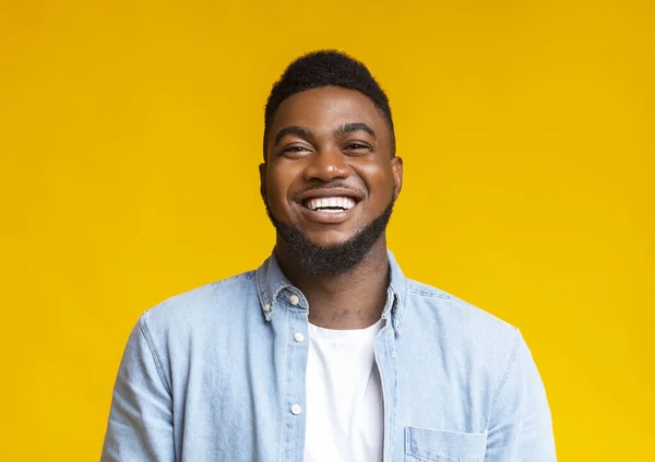 Portrait of young laughing african american guy over yellow background — Stock Photo, Image