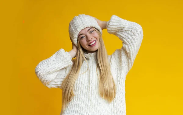 Rapariga positiva com chapéu de malha branco sobre fundo amarelo — Fotografia de Stock