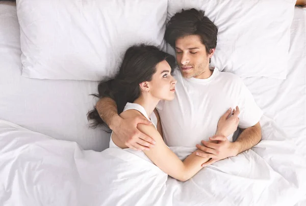 Joven pareja amorosa durmiendo en la cama y abrazándose — Foto de Stock