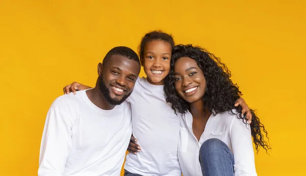 Smiling African American father, mother and daughter over yellow background — Stock Photo, Image