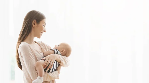 Mujer sosteniendo bebé recién nacido y mirando con amor y cuidado — Foto de Stock