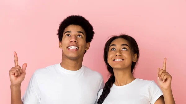 Excited teen couple pointing and looking upwards — Stock Photo, Image