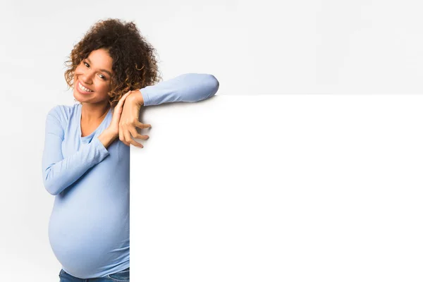 Mujer embarazada negro feliz con cartelera, fondo claro —  Fotos de Stock