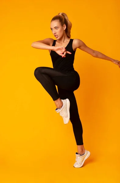 Sporty Lady saut d'exercice en studio sur fond jaune — Photo