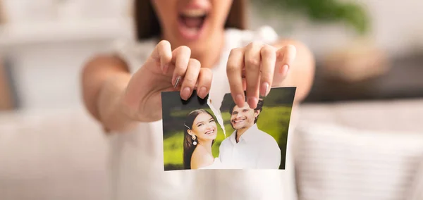 Irreconocible chica rasgando aparte foto de feliz pareja interior, recortado —  Fotos de Stock