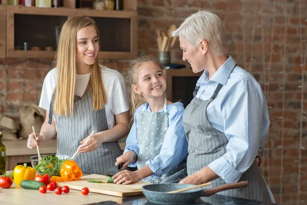 Adulto señoras alegres enseñando niña cómo cocinar —  Fotos de Stock