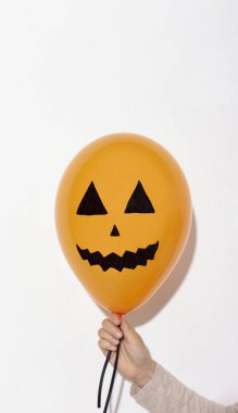 Korkunç turuncu cadılar bayramı balonu kadının elinde beyazın üstünde