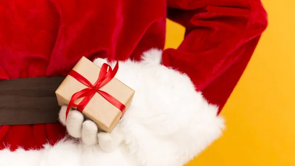 Santa Claus sosteniendo regalo de Navidad en la mano a sus espaldas —  Fotos de Stock