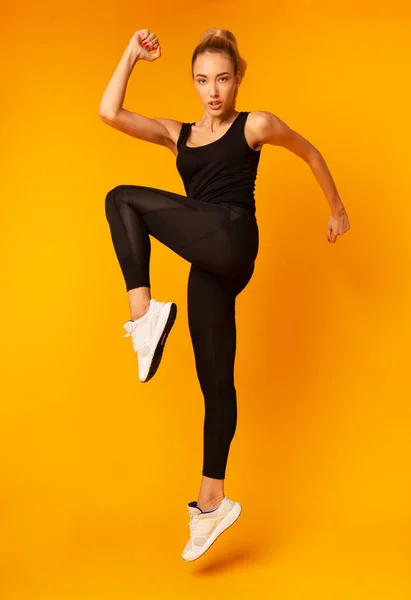Fitness Vrouw springen tijdens het sporten op gele achtergrond, Studio Shot — Stockfoto