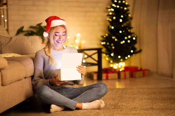 Christmas time. Happy girl with santa hat opening gift box — Stock Photo, Image