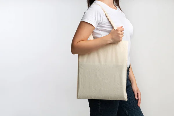 Жінка тримає порожній еко сумку над білим фоном студії, обрізаний — стокове фото