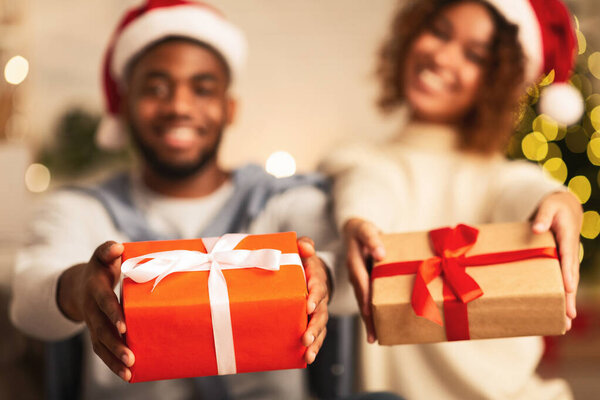 African-american couple stretching gift boxes to camera