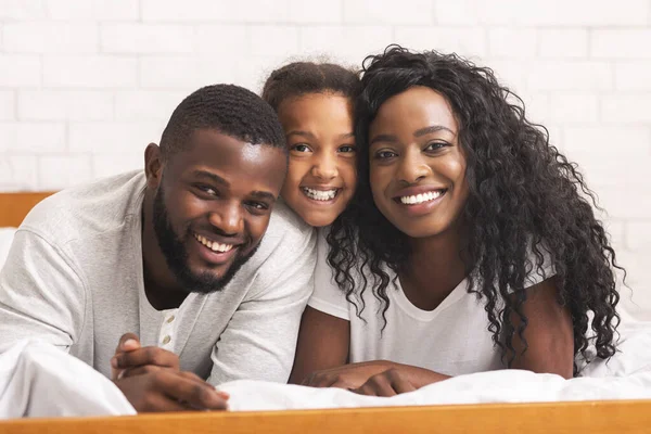 Retrato da bela família afro-americana deitada na cama juntos — Fotografia de Stock