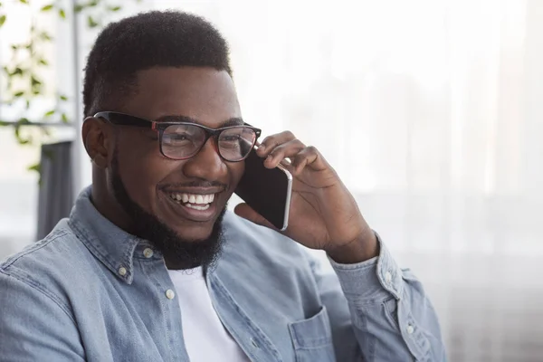 Fröhlicher schwarzer Kerl mit Brille, der auf dem Handy spricht — Stockfoto