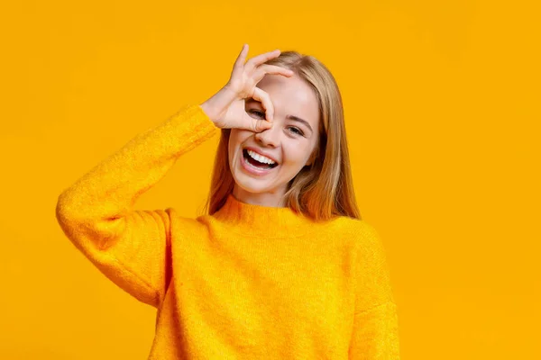 Joyful girl showing ok sign, holding fingers near her eye — Stock Photo, Image