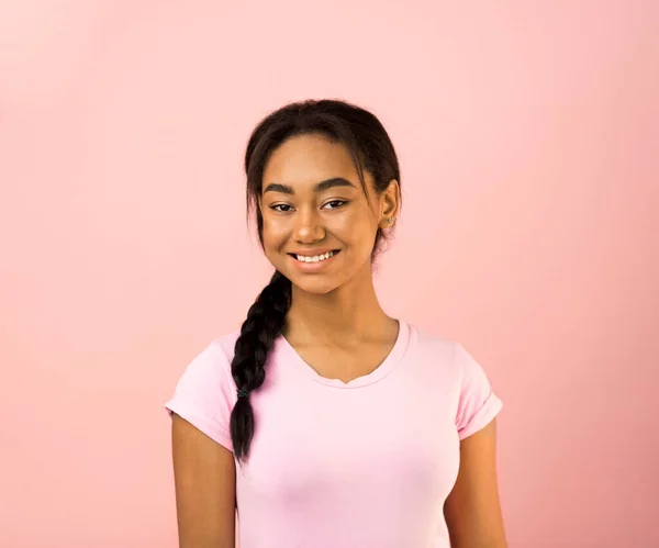 Chica alegre en camiseta rosa sonriendo a la cámara, fondo rosa — Foto de Stock