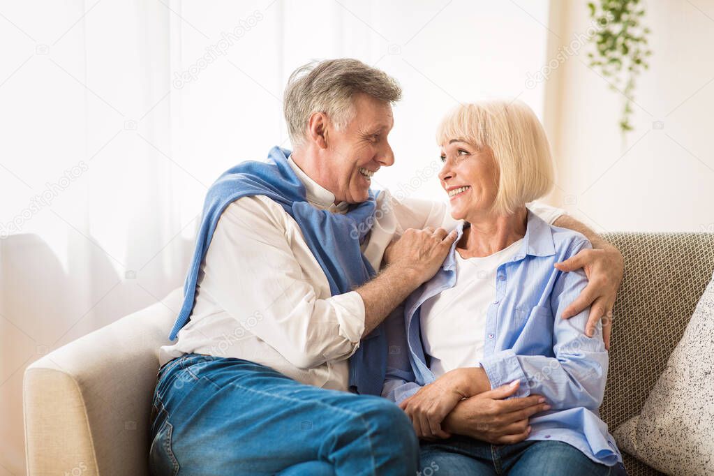 Excited senior couple talking and relaxing at home