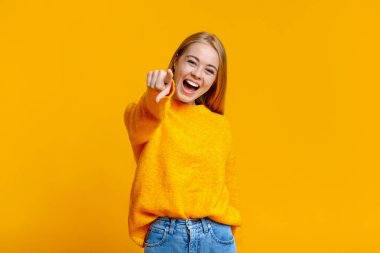 Kız gülüyor, dalga geçiyor, kamerayı işaret ediyor.