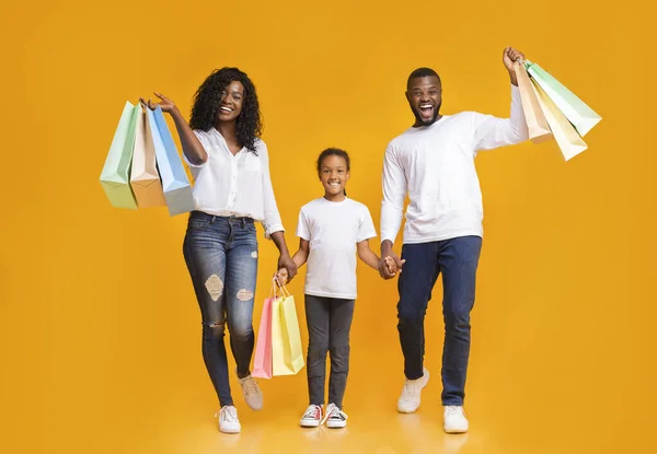 Os pais e sua filha levando sacos de compras e sorrindo — Fotografia de Stock