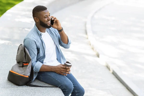 Alegre preto cara falando no telefone ao ar livre e beber café — Fotografia de Stock