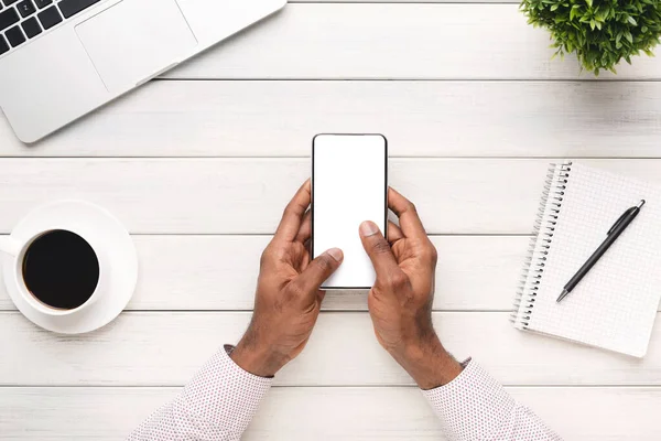 Чорний чоловік використовує сучасний смартфон з порожнім екраном на робочому місці — стокове фото