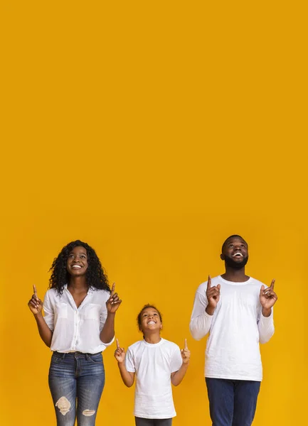 Beautiful Black Family Pointing Fingers Upwards At Copy Space