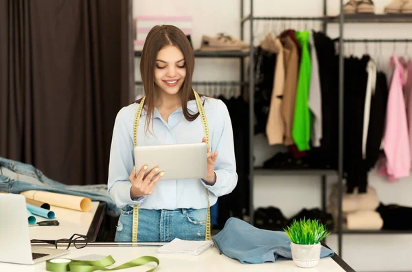 Menina alfaiate usando esboço de tablet digital em oficina de design de roupas — Fotografia de Stock