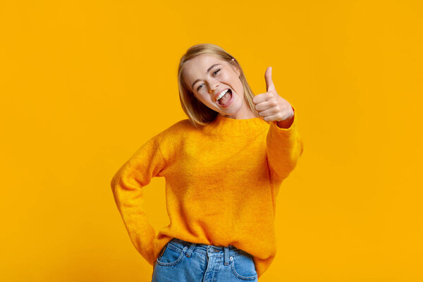Carefree teen girl showing thumb up, recommending something