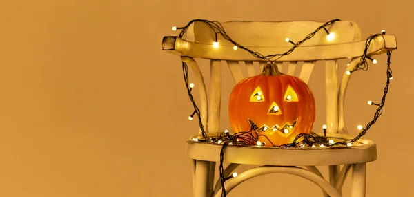 Calabaza naranja con luces de guirnalda en silla —  Fotos de Stock