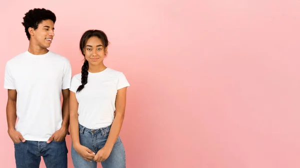 Unga vänner poserar, kille tittar på flicka över rosa bakgrund — Stockfoto