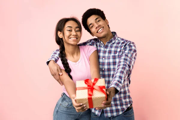 Joyeux jeune couple étirant boîte cadeau à la caméra — Photo