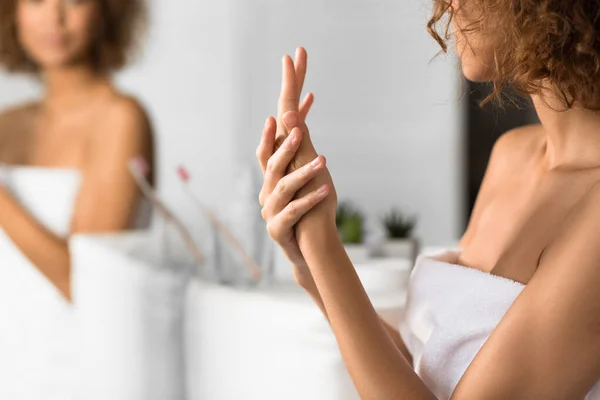 Mujer irreconocible aplicación de crema de manos en el baño —  Fotos de Stock