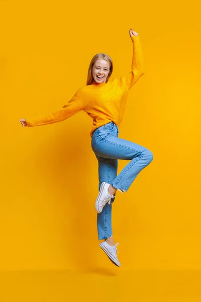 Gelukkig jong meisje springen in studio en kijken naar camera — Stockfoto