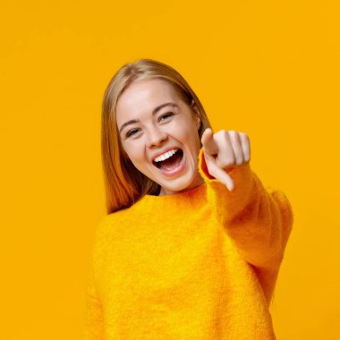 Genç kız birine gülüyor ve kamerayı işaret ediyor.