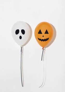 İki tatil balonu beyaz üzerinde uçan yüzler çiziyor.