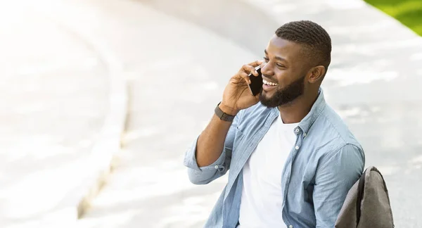 Bonito preto millennial cara falando no telefone ao ar livre e rindo — Fotografia de Stock