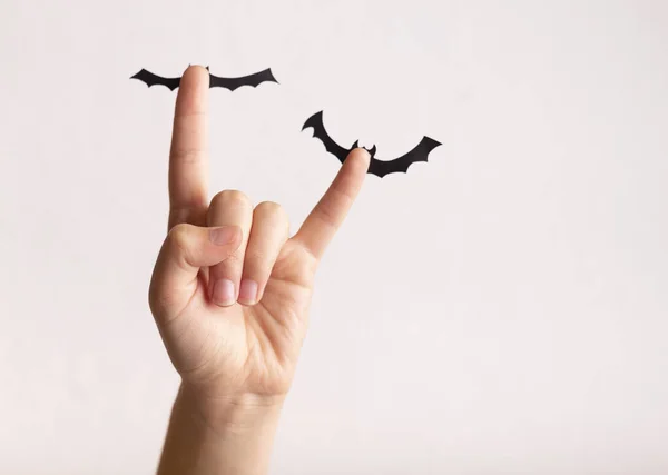 Woman hand putting up on hands paper bats on white