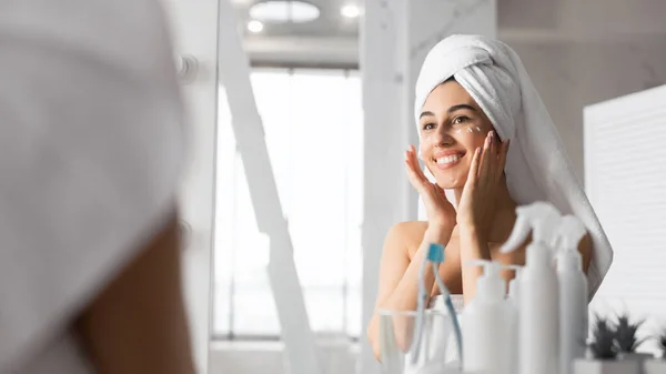 Chica aplicando crema para los ojos en la piel de pie en el baño, Panorama — Foto de Stock