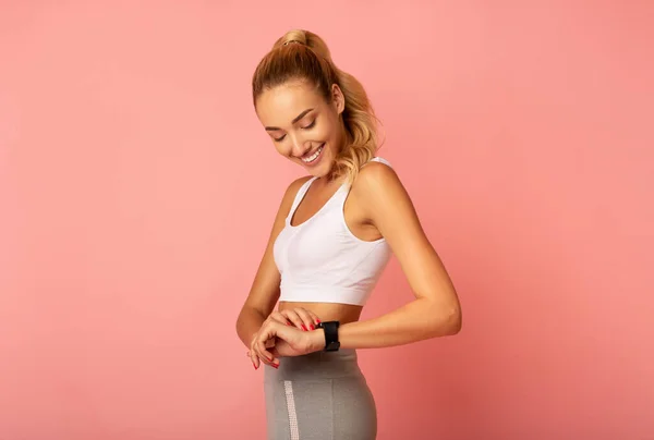 Donna sportiva che utilizza Smartwatch durante l'allenamento in piedi su sfondo rosa — Foto Stock