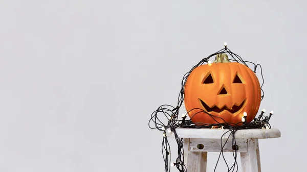 Cabeza de calabaza naranja con cara sonriente y guirnalda sobre gris —  Fotos de Stock