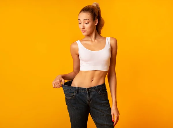 Mulher magro em tamanho grande jeans posando em pé no estúdio — Fotografia de Stock