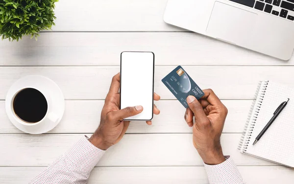 Μαύρος άνδρας κρατώντας smartphone με λευκή οθόνη και πιστωτική κάρτα — Φωτογραφία Αρχείου