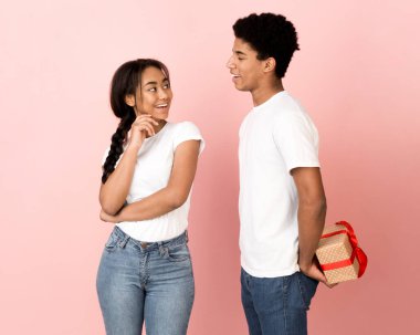 Sevgilisinden hediye saklayan mutlu adam, pembe arka plan.