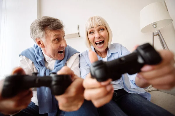 Alegre pareja de ancianos jugando videojuegos en casa — Foto de Stock