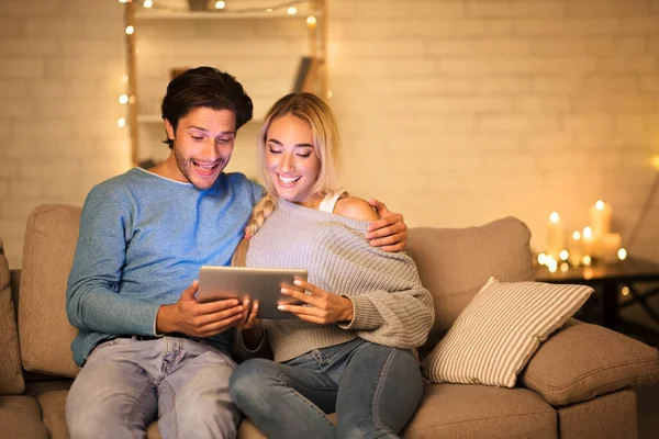 Nadšený pár pomocí digitálního tabletu v útulném obývacím pokoji — Stock fotografie