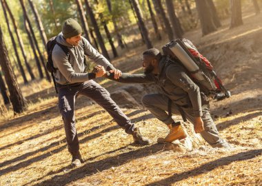 Bir adam diğerine tırmanırken yardım ediyor.