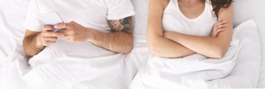 Adam kırgın karısını yatakta görmezden geliyor, video oyunu oynuyor.