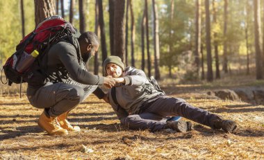 Zenci adam yaralı arkadaşının kalkmasına yardım ediyor.