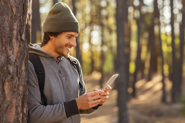 Szczęśliwy człowiek z plecakiem rozmawiający z przyjaciółmi w lesie — Zdjęcie stockowe