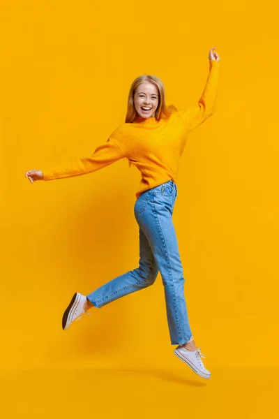 Портрет милой девочки-подростка, прыгающей на оранжевом фоне — стоковое фото